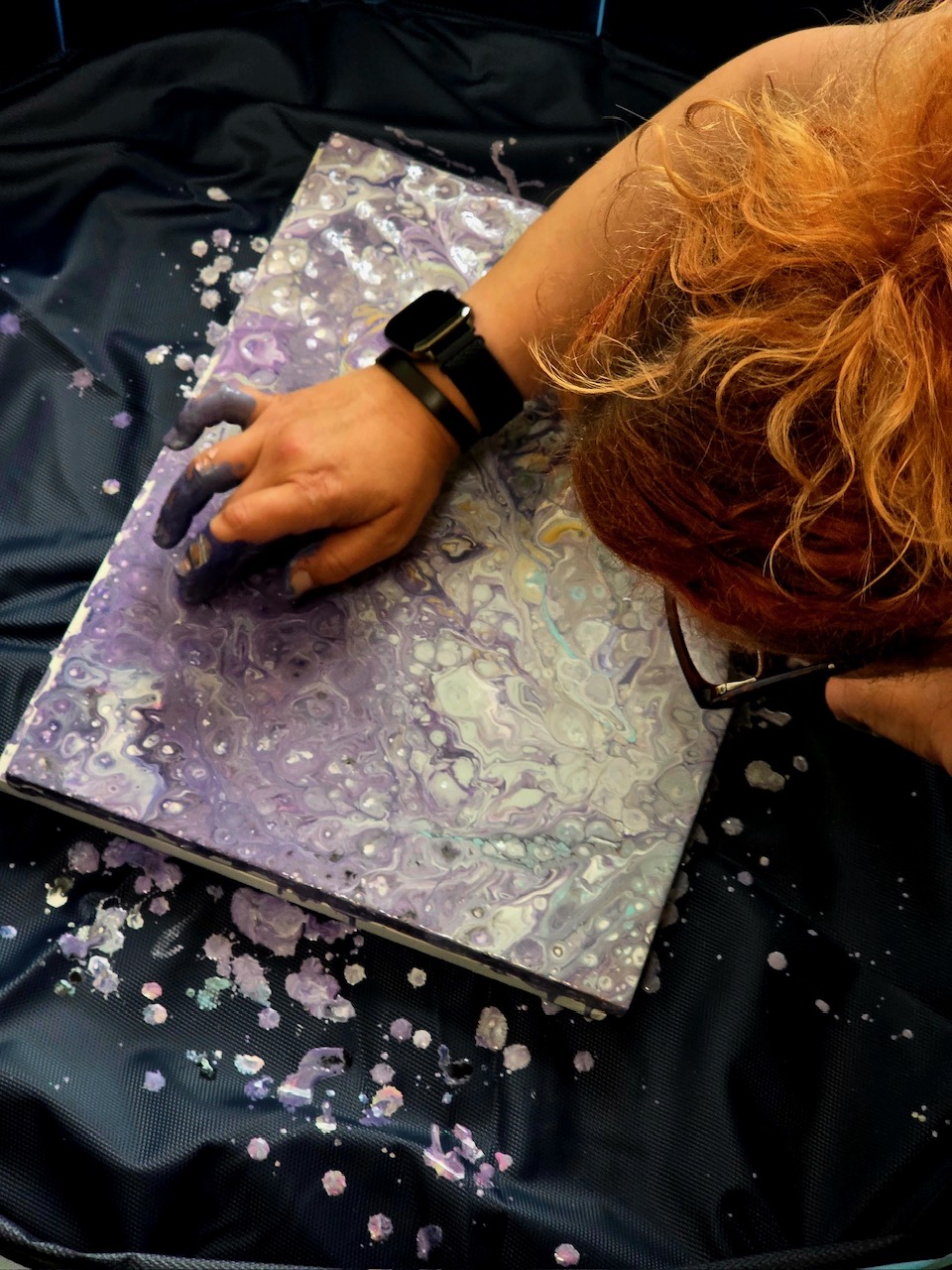 Artist leaning over a fluid art canvas while working
