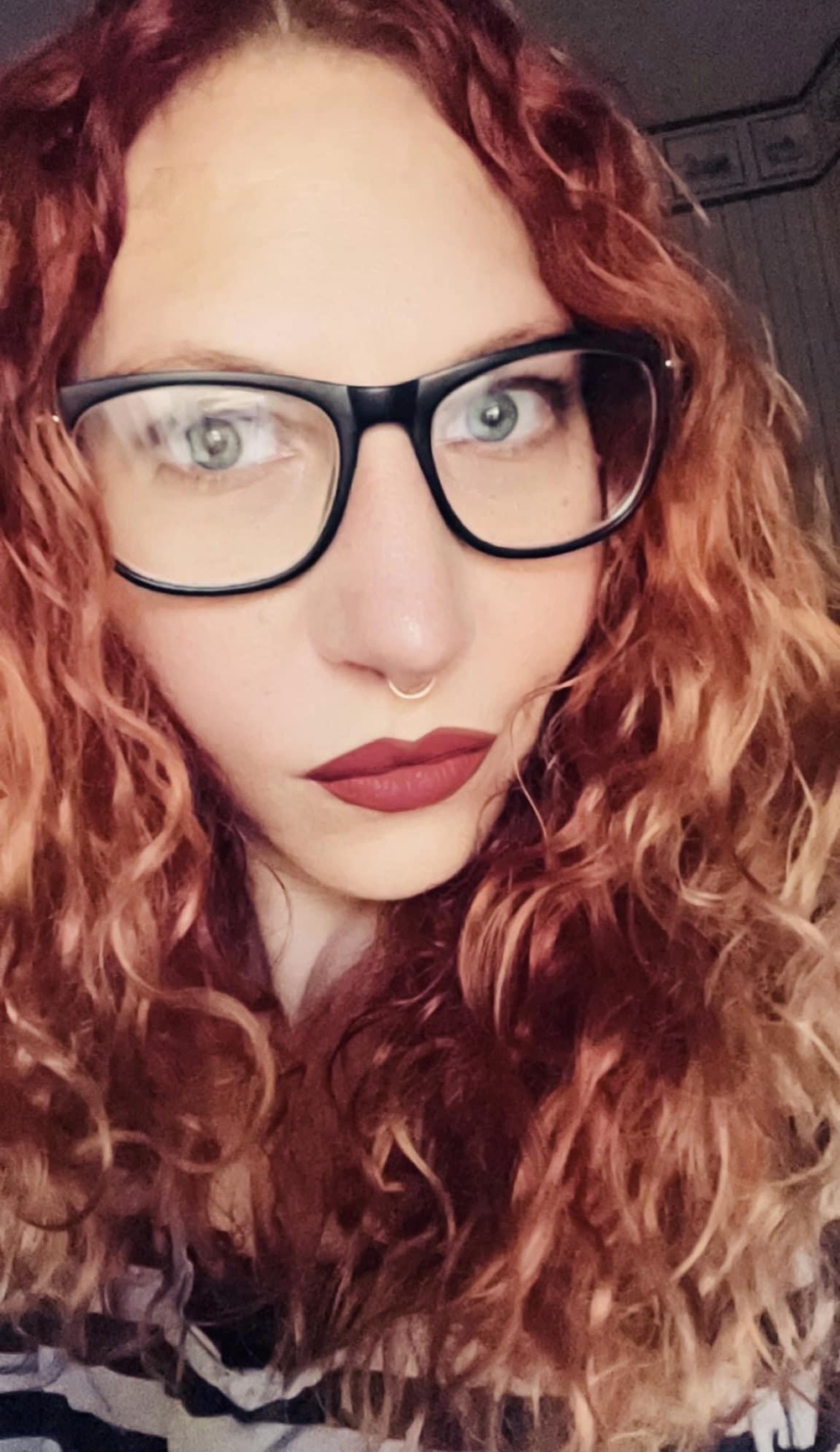 Portrait of Inferna with red curls and glasses